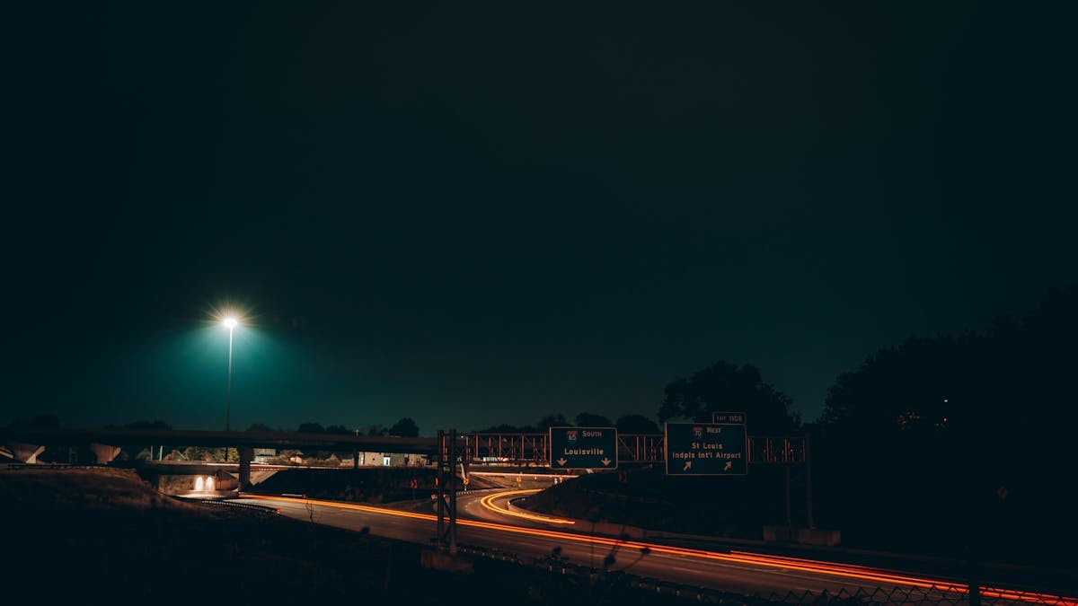 Captivating long exposure shot of Indianapolis highway at night with light trails and road signs.